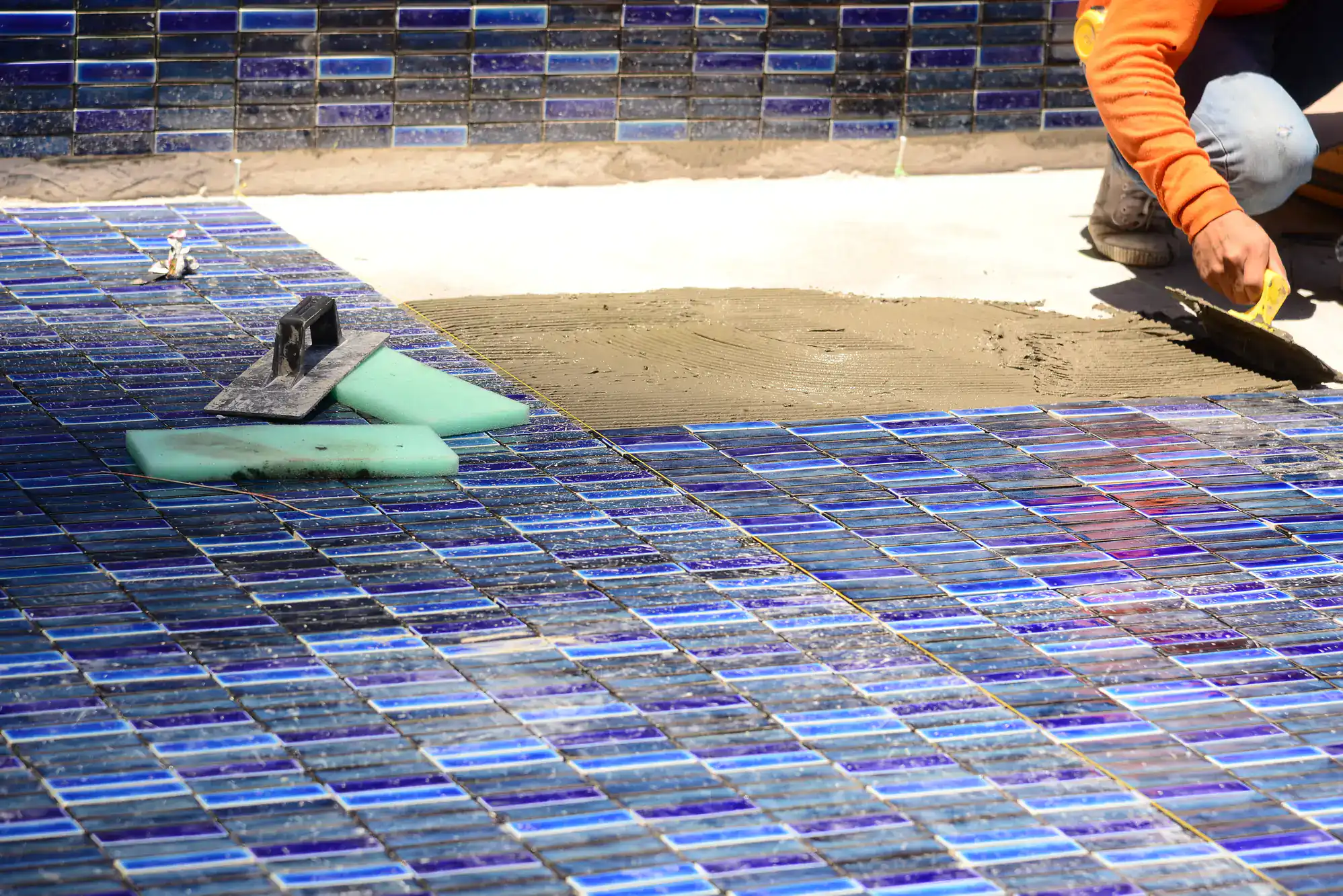 A tile floor with a spatula and sponge.