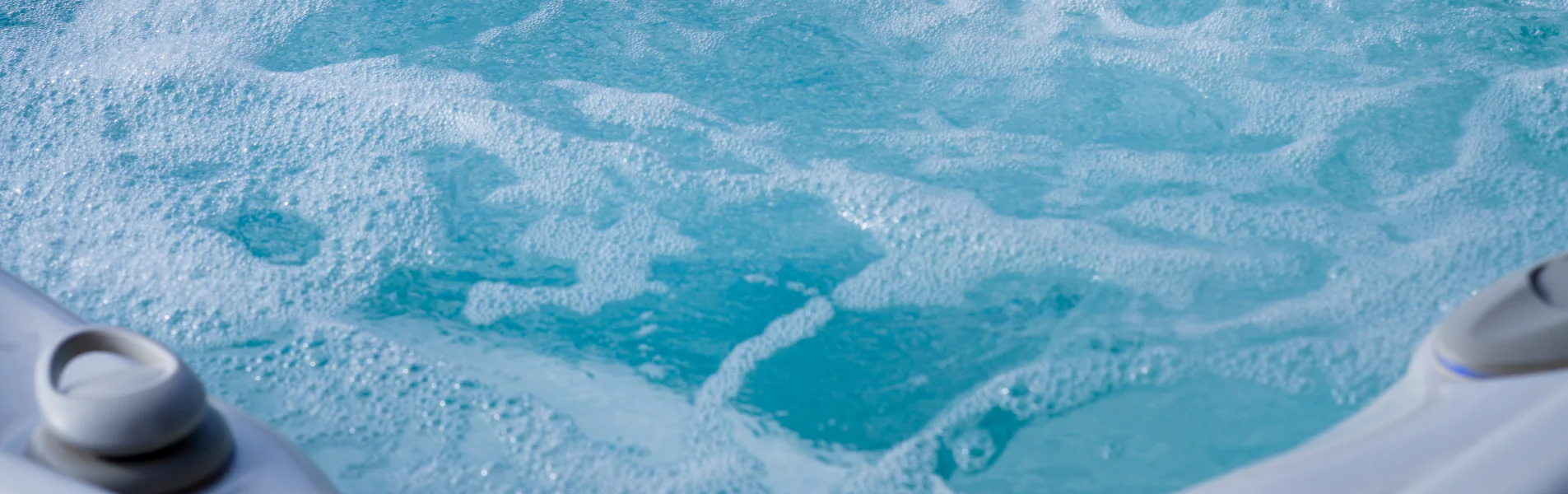Close-up of bubbling water in a hot tub or jacuzzi, with white foam and water jets visible at the edges. The scene conveys a sense of relaxation and leisure.